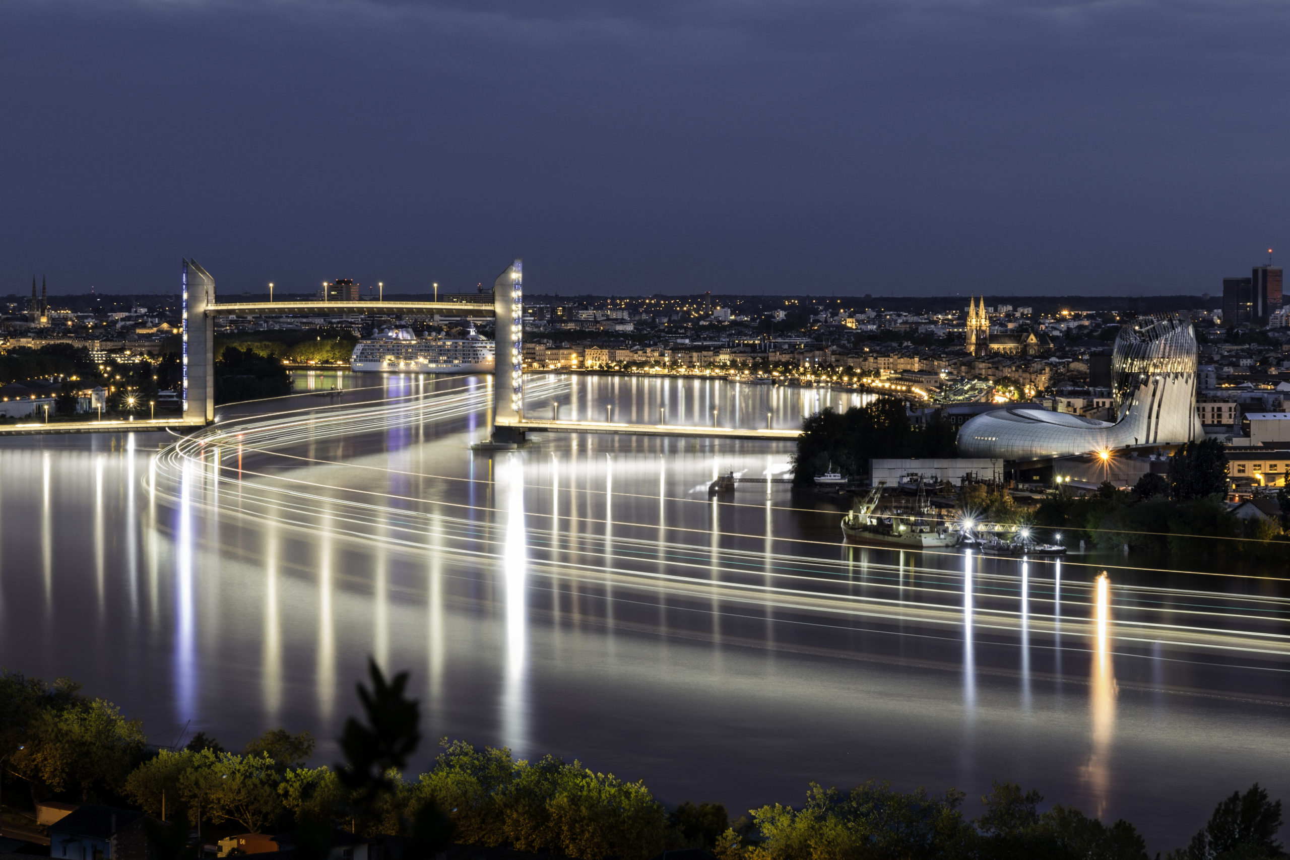 Long time exposure (718 seconds) of a cruising ship leaving Bordeaux (France) by night and getting through the raised deck of Chaban-Delmas bridge. On the right is the new "Cité du Vin" (Wine museum) Pose longue (718 secondes) d'un paquebot quittant Bordeaux de nuit et passant sous le tablier central du pont Chaban-Delmas. A droite, la Cité du Vin